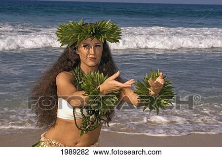 Stock Image - Hula Dancer In Ti-Leaf Skirt, Haku, Lei, In A Dancing Pose On The Beach. Fotosearch