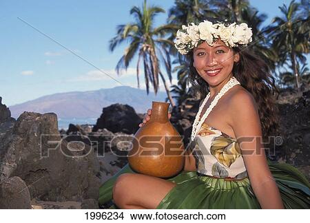 Picture - Hula Dancer Squatting With Ipu Ti Leaf Skirt Shell Lei Gardenia Haku Beach Rocks Palms Mountains Background. Fotosearch