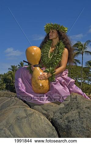 Hula Dancer With Haku Lei In Traditional Outfit On Rocky Shore Holding Ipu, Palm Tree Background View Large Photo Image Picture - Hula Dancer With Haku Lei In Traditional Outfit On Rocky Shore Holding Ipu, Palm Tree Background. Fotosearch