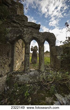 Stock Photo - Hume Park, Statue seen through arched window of ruined building; Alnwick, Northumberland, England, UK. Fotosearch