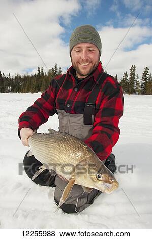 Stock Photo - Ice fisherman holding a large whitefish; Ontario, Canada. Fotosearch