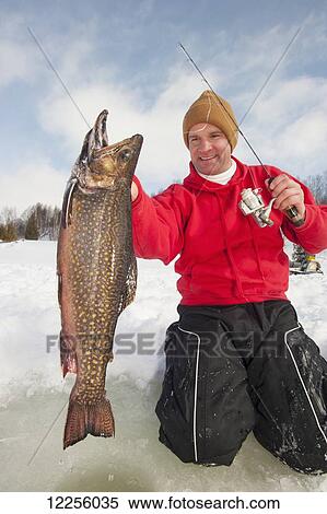 Stock Photography - Ice fisherman holding a large winter brook trout; Ontario, Canada. Fotosearch