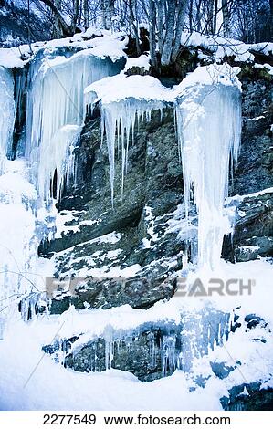 Stock Photo - Icicles at the roadside from a frozen stream and waterfall caught in stasis, contrasting against the dark rocks; Ortnevik, Sognefjord, Norway. Fotosearch