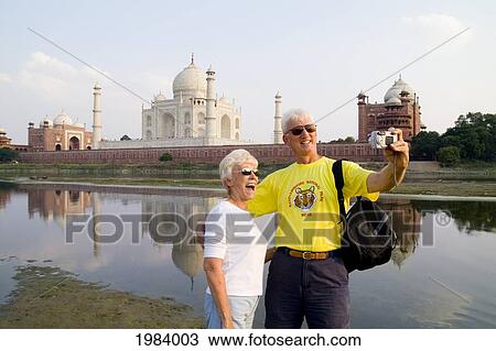 Stock Image - India, Agra, Tourist Couple Taking Photo Of Themselves In Front Of The Taj Mahal.. Fotosearch