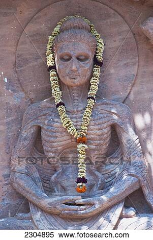 Stock Photography - India, Bihar, Statue of the Buddha at the Mahabodhi Temple depicting his austerity/starvation phase. Puja flowers around his body. Bodhgaya; Bohdgaya. Fotosearch