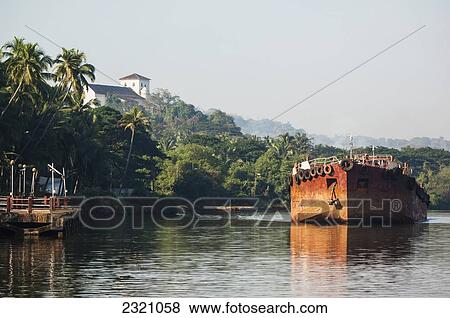 Stock Photo - India, Cargo Barge On The Mandovi River With Chapel Of St Catherine In Background; Old Goa. Fotosearch