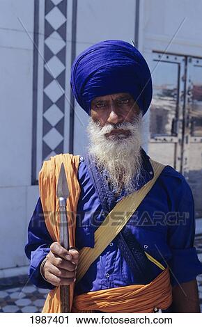 Stock Image - India, Gwalior, Sikh Senior Man With White Beard And Bloodshot Eyes, Holding Spear.. Fotosearch