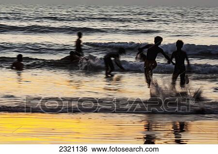 Stock Photograph - India, Karnataka, Blurry Figures In Crashing Waves At Gokarna Beach; Gokarna. Fotosearch
