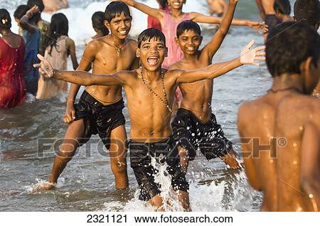 Stock Image - India, Karnataka, Boys Playing In Water; Gokarna. Fotosearch