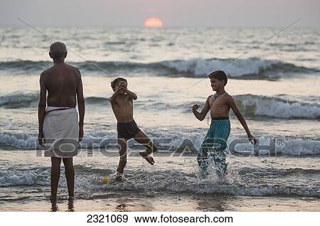 India, Karnataka, Boys Playing; Gokarna, Hindu Pilgrim Praying By Ocean At Sunset View Large Photo Image Stock Photo - India, Karnataka, Boys Playing; Gokarna, Hindu Pilgrim Praying By Ocean At Sunset. Fotosearch