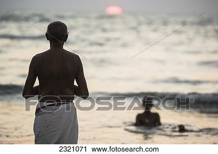 India, Karnataka, Hindu Pilgrim Praying By Ocean At Sunset; Gokarna View Large Photo Image Stock Image - India, Karnataka, Hindu Pilgrim Praying By Ocean At Sunset; Gokarna. Fotosearch
