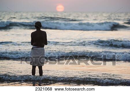 India, Karnataka, Hindu Pilgrim Praying By Ocean At Sunset; Gokarna View Large Photo Image Stock Photo - India, Karnataka, Hindu Pilgrim Praying By Ocean At Sunset; Gokarna. Fotosearch