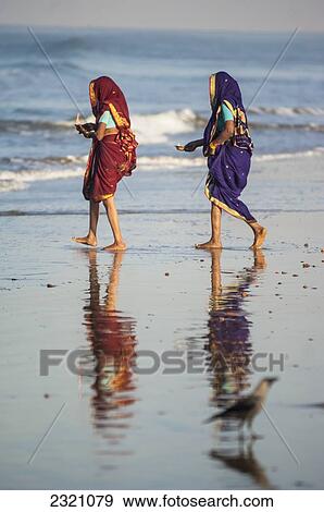Stock Photo - India, Karnataka, Two Woman In Traditional Saris Making Offerings In Sea; Gokarna. Fotosearch