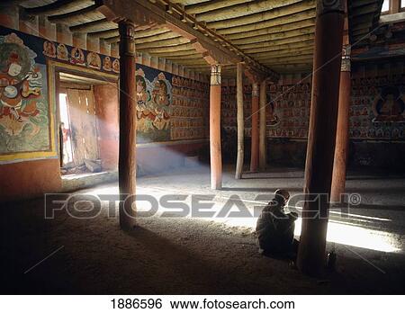 Stock Photograph - India, Ladakh, Old Man Praying In Tsemo Monastery With Ray Of Light Coming Through Doorway; Leh. Fotosearch