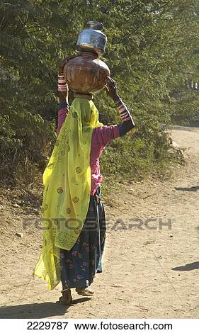 Stock Photo - India, Rajasthan, Woman With One Terracotta And One Tin Water Pot On Her Head; Nimaj. Fotosearch