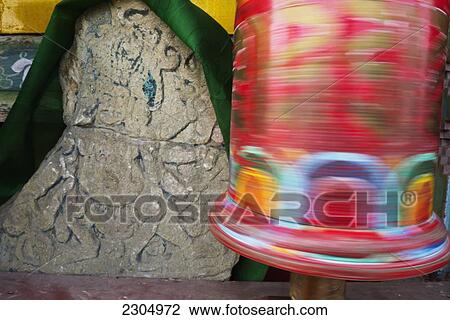 Stock Image - India, Spinning prayer wheel and Buddhist rock carving on the outer walls of Pemayangtse Monastery; West Sikkim. Fotosearch