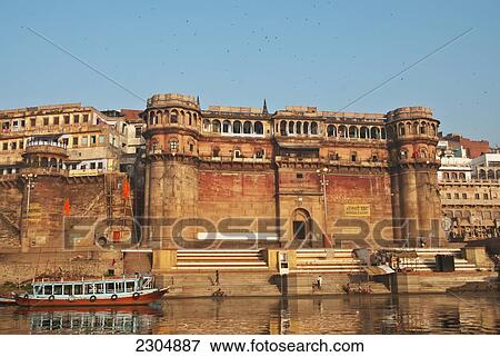 Stock Photo - India, Uttar Pradesh, taken from a boat on the Ganges; Varanasi, Bonsale Ghat with blue & red wooden boat. Fotosearch