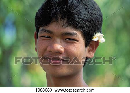 Indonesia, Bali, Headshot Of Smiling Young Man, Outdoors Flower In Ear No Model Release View Large Photo Image Stock Photo - Indonesia, Bali, Headshot Of Smiling Young Man, Outdoors Flower In Ear No Model Release. Fotosearch