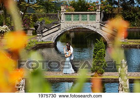 Stock Image - Indonesia, Bali, Karangasem, Wedding Couple Walking On Tirtagangga Water Palace Gardens.. Fotosearch