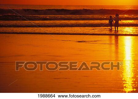 Picture - Indonesia, Bali, Kuta Beach At Sunset, Children Play In Shoreline, Orange Sky No Model Release. Fotosearch