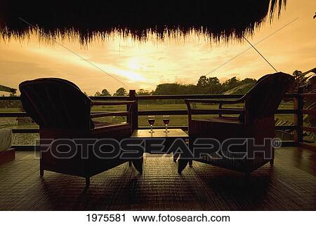 Stock Image - Indonesia, Bali, Sunset View From Bungalow Terrace With Wine Glasses; Ubud. Fotosearch