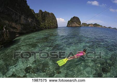 Indonesia, Banda Sea, Misool Islands, View From Above Of Woman Snorkeling Over Shallow Reef, Islands In Background View Large Photo Image Stock Photography - Indonesia, Banda Sea, Misool Islands, View From Above Of Woman Snorkeling Over Shallow Reef, Islands In Background. Fotosearch