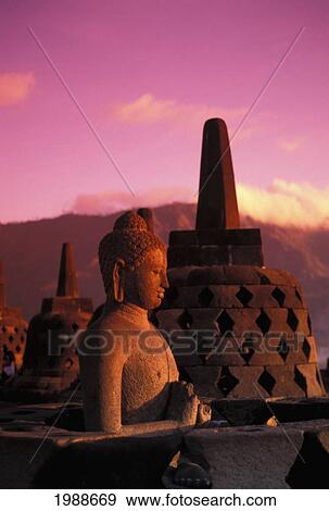 Stock Photo - Indonesia, Java, Borobudor Temple And Buddha Statue At Sunrise, Pink Misty Sky. Fotosearch