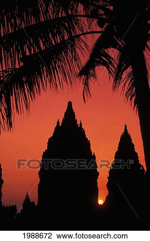 Stock Image - Indonesia, Java, Prambanan, Silhouette Of Temple At Sunset With Palm Tree. Fotosearch