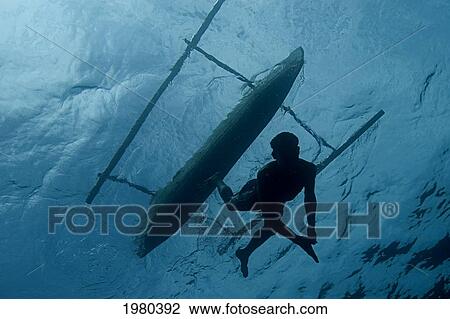 Stock Image - Indonesia, Pura Island, Native Freediver Swims Down From His Canoe, View From Below.. Fotosearch