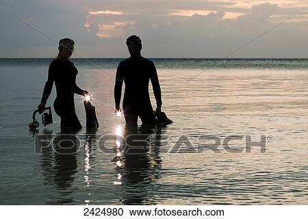 Indonesia, Silhouetted divers entering the ocean with lights at dusk View Large Photo Image Stock Image - Indonesia, Silhouetted divers entering the ocean with lights at dusk. Fotosearch