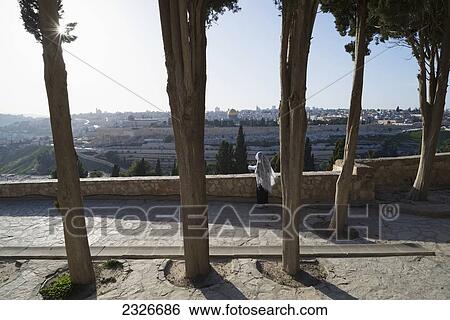 Stock Photograph - Israel, Pilgrim praying on Mount of Olives facing Old City; Jerusalem. Fotosearch