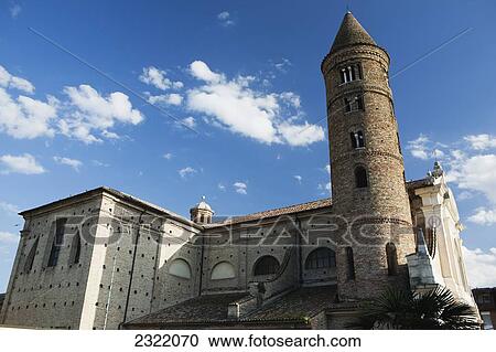 Stock Image - Italy, Emilia-Romagna, Ravenna, Basilica Di San Vitale, Brick round tower and stone church against sky with clouds. Fotosearch