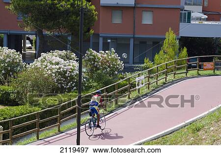 Stock Photo - Italy, Marche, Cyclist up hill on cycle lane; Lido Tre Archi. Fotosearch