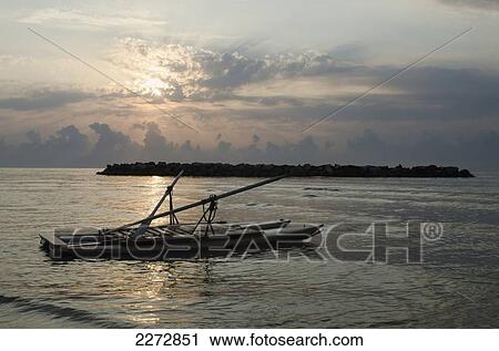 Stock Image - Italy, Marche, Floating raft on calm sea at sunrise with clouds and rocks; Porto San Giorgio. Fotosearch