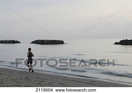 Italy, Marche, Jogger running on beach at sunrise; Porto San Giorgio View Large Photo Image Picture - Italy, Marche, Jogger running on beach at sunrise; Porto San Giorgio. Fotosearch