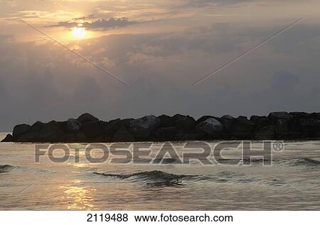 Stock Photo - Italy, Marche, Sunrise on Adriatic sea with rocks and clouds; Porto San Giorgio. Fotosearch