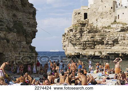 Italy, Puglia, Polignano a Mare beach is a picturesque swath of golden sand that slips into bright clear green water and is lined by sheer cliffs.; Polignare del Mare View Large Photo Image Picture - Italy, Puglia, Polignano a Mare beach is a picturesque swath of golden sand that slips into bright clear green water and is lined by sheer cliffs.; Polignare del Mare. Fotosearch