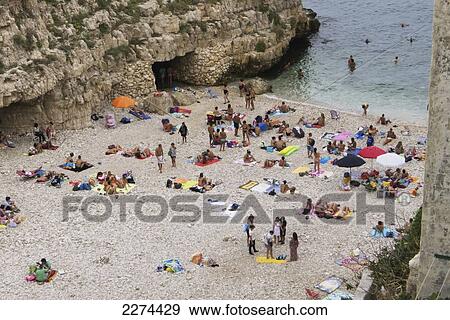 Italy, Puglia, Polignano a Mare beach is a picturesque swath of golden sand that slips into bright clear green water and is lined by sheer cliffs; Polignare del Mare View Large Photo Image Stock Photo - Italy, Puglia, Polignano a Mare beach is a picturesque swath of golden sand that slips into bright clear green water and is lined by sheer cliffs; Polignare del Mare. Fotosearch