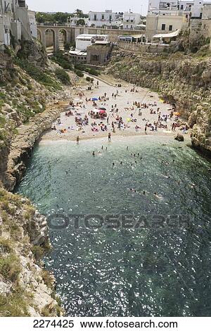 Stock Photography - Italy, Puglia, Polignano a Mare beach is a picturesque swath of golden sand that slips into bright clear green water and is lined by sheer cliffs.; Polignare del Mare. Fotosearch