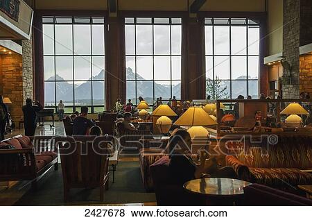 Stock Photo - Jackson Lake Lodge, guests in lobby with storm brewing outside, view at Teton Mountains; Wyoming, United States of America. Fotosearch