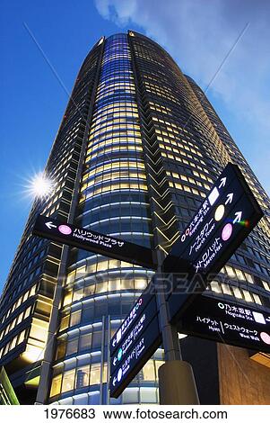 Stock Image - Japan, Roppongi Hills at dusk; Tokyo, Directional sign and Mori Tower. Fotosearch