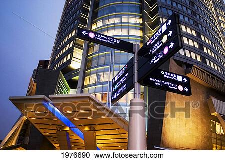 Stock Image - Japan, Roppongi Hills at dusk; Tokyo, Directional sign and Mori Tower. Fotosearch