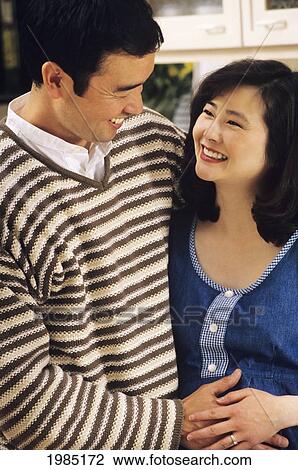 Japanese Couple Embracing In Kitchen, Man Feeling Woman's Pregnant Stomach. View Large Photo Image Stock Image - Japanese Couple Embracing In Kitchen, Man Feeling Woman's Pregnant Stomach.. Fotosearch