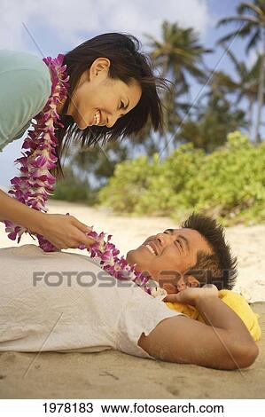 Stock Image - Japanese Couple On The Beach Wearing Leis.. Fotosearch