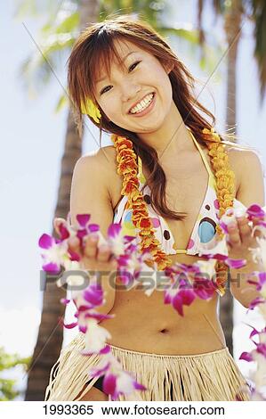 Stock Photography - Japanese Girl In Hula Skirt Holding Out A Lei. Fotosearch
