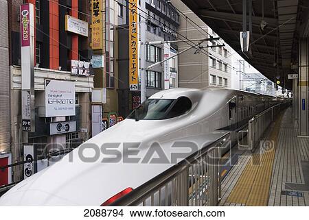 Picture - Japanese High Speed Train Waiting At The Station With Buildings Close Behind; Tokyo, Japan. Fotosearch