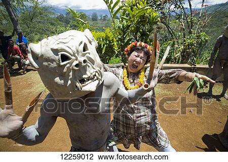 Stock Image - Japanese woman joins in a performance by the Goroka Mudmen; Goroka, Eastern Highlands, Papua New Guinea. Fotosearch