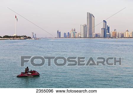 Stock Photograph - Jet skier with the skyline of Abu Dhabi in the background; Abu Dhabi, United Arab Emirates. Fotosearch