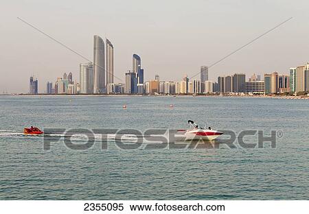 Stock Photography - Jet skiers with the skyline of Abu Dhabi in the background; Abu Dhabi, United Arab Emirates. Fotosearch