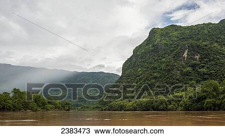 Stock Image - Jungle and a muddy river; Muang Ngoy, Laos. Fotosearch